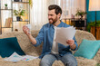 © Andrii Iemelianenko - Young man at home sits on sofa, frustrated disappointed, nervously crumpling a paper and tossing it away. Caucasian guy reviews financial documents, stressed about bankruptcy, debt and unpaid bills