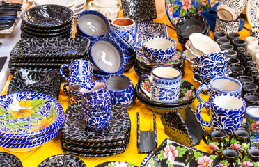 Wall Mural - A table full of blue and white dishes and cups. The table is covered with a yellow cloth. City of Puebla, Mexico, crafts