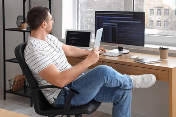 Relaxed male programmer with tablet computer working in office