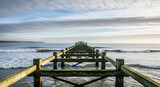 View of Hastings Pier remains, wooden structure stretching into the sea with waves and cloudy sky, Sussex, UK
