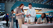 © Andrey Popov - Engaging Audience At Trade Show: Saleswoman Presents Diverse