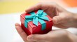 © Sukandi - Red gift box with turquoise ribbon delicately held in caring hands