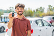 © luismolinero - Young Arabian handsome man holding car key at outdoors with happy expression