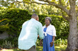 © wavebreak3 - Senior couple enjoying conversation under tree in sunny garden, smiling warmly
