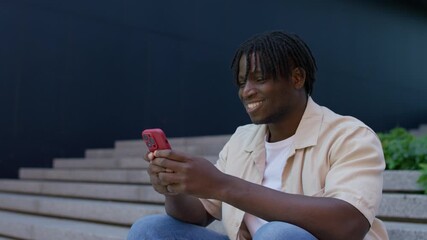 Smiling young man typing message on smartphone