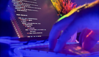 Developer typing Python code in neon-lit workspace