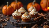 Autumn-themed dessert display featuring pumpkin cupcakes with cream frosting on a rustic wooden board, surrounded by decorative pumpkins and spices