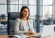 © InfinityVisuals - Professional in a Modern Office: A poised woman in a smart blazer sits at her office desk, radiating confidence as she navigates her laptop in an elegant, well-lit space.