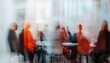© Studicon - The photograph shows several individuals gathered for a meeting, their forms slightly obscured by motion blur, seated around a table in a brightly lit room.