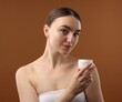 © New Africa - Beautiful woman with jar of face cream on brown background