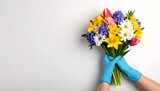 Hands in blue gloves holding a colorful spring bouquet