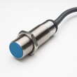 © Jeab - Close up of a metal proximity sensor with a blue indicator and black cable on a white background