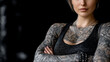 © Maksym - Female tattoo artist with bold and artistic tattoos covering arms and torso, black background with subtle shadows, copy space around for creative use