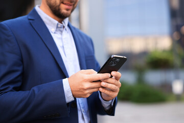 Businessman using smartphone outdoors, closeup. Space for text