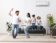 © New Africa - Happy family having fun in living room. Air conditioner keeping comfortable temperature in room