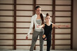 © DragonImages - Caucasian young woman assisting child girl practicing gymnastics balance exercise in gym, both focused on movement, wooden wall bars visible in background