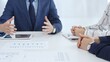 © volha_r - Business professionals discussing financial charts on tablet, collaborating closely while reviewing project data in modern corporate workspace