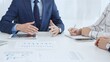 © volha_r - Business team collaborating in an office, analyzing financial data through digital tablets and documents during a meeting. Close up view of hands engaged in discussion and strategy planning