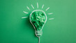 © Daria - Creative concept depicting a green crumpled paper inside a sketched lightbulb symbolizing innovative eco-friendly ideas and sustainable energy solutions on green background