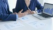 © rogerphoto - Businessman and business woman reviewing financial documents, collaborating over laptop screen, analyzing market charts for strategic corporate planning. Businesspeople and finance concept