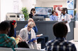 © DC Studio - Busy hospital waiting room with elderly male doctor discussing treatment plans with mother and daughter. Female healthcare workers assist patients and manage medical records nearby.