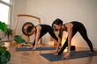 © phoenix021 - Two middle aged woman doing yoga practice indoors in yoga studio gong and plants around them