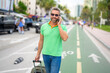 Mature man traveler with phone outdoor. Tourist traveler on spring vacation. Travelers luggage for spring trip. Summer tour. Tropical getaway. Spring break. A traveler enjoys summer day. Summer trip.