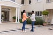 © wavebreak3 - African American couple standing outside home, holding hands and smiling warmly
