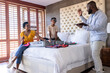 © wavebreak3 - Family packing suitcase on bed, preparing for vacation with excitement and laughter