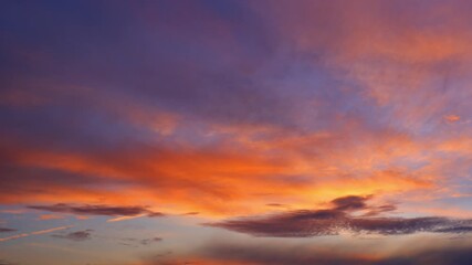 Wall Mural - a sunrise sky timelapse reveals sweeping clouds painted in vivid orange and purple. light softly bre