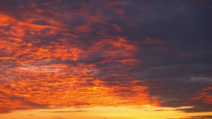 Wall Mural - A sunset sky timelapse, glowing in fiery orange and deep purple hues, conveys the concept of passion, symbolizing energy, transformation, and the fleeting yet powerful beauty of nature’s cycle.
