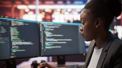 Focused Black woman coding on dual monitors, software development, programmer, technology, programming, coding, indoors, business