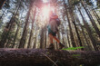 © olezzo - Hiker woman balancing on fallen tree trunk in forest