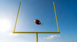 © BimoPrinting - Game winning field goal attempt with football soaring through goalposts against vibrant blue sky, perfect for sports advertising and athletic success imagery