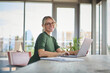 © Westend61 - Smiling woman with glasses working on laptop at home in natural light
