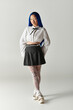 © Bliss - Confident young woman with vibrant blue hair poses in a minimalist studio