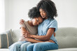 © Louis-Paul Photo - Affectionate mother and daughter sitting on sofa at home