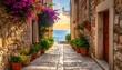 © Geriano - A narrow cobblestone street lined with potted flowers and stone buildings leads to a vista of ocean and sunset