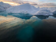 © Marcin Dobas - Massive iceberg in calm Arctic waters with deep blue submerged base under a pastel-colored sky.