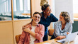 © (JLco) Julia Amaral - Three smiling adults enjoying a moment of laughter in a cozy office setting