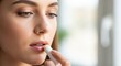 © Elenba - Woman using lip balm for moisturizing lips, ensuring a gentle touch and soft appearance. Lip balm application hydrates and protects against dryness, offering rejuvenation for sensitive skin.
