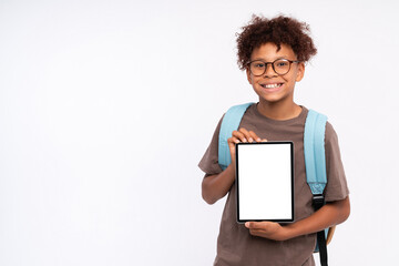 Smiling African-American school preteen boy elementary primary pupil holding using digital tablet for e-learning showing demonstrate mock up empty screen isolated over white background copy space