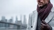 © David Zarzosa - Stylish man in gray coat and scarf standing outdoors in city on cold day, winter fashion with leather gloves and urban background with copy space.