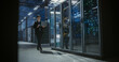 © Aleksei Gorodenkov/Stocksy - Wide view of technician walking in data center.