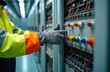 © miss irine - Technician wearing high-visibility jacket, safety gloves adjusts components in power grid substation. Electrical system maintenance involves intricate wiring, control panels, technical expertise for