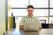 © Dani Nahuel/Stocksy - Smiling Latin Man Working on Laptop at Office