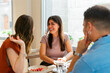 © Peninsula/Stocksy - Group of young adults talking at a table in a restaurant