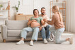 © Pixel-Shot - Young happy pregnant woman with her husband and doula sitting on sofa at home