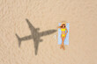 © New Africa - Woman sunbathing on beach, top view. Flying airplane casting shadow on sand