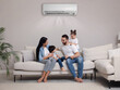 © New Africa - Happy family on sofa in living room. Air conditioner keeping comfortable temperature in room